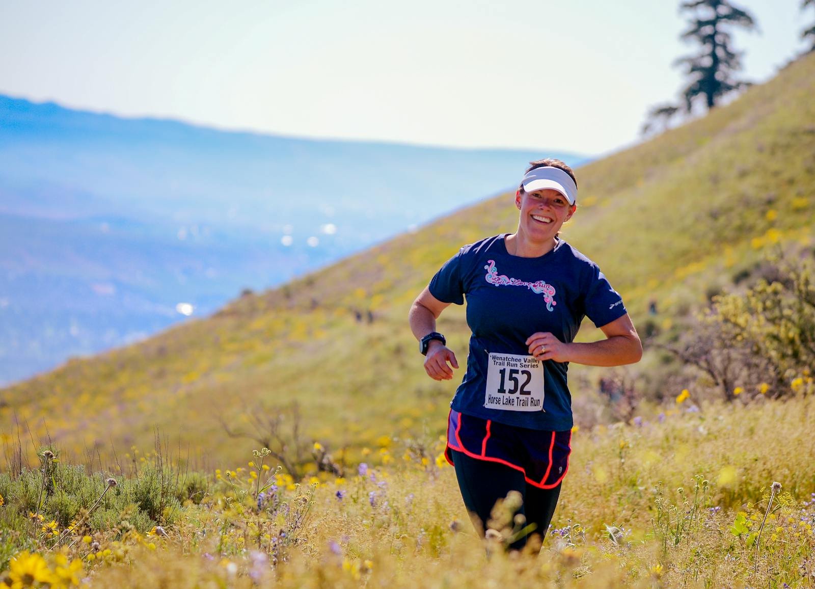 Woman trail running on a hillside in summer